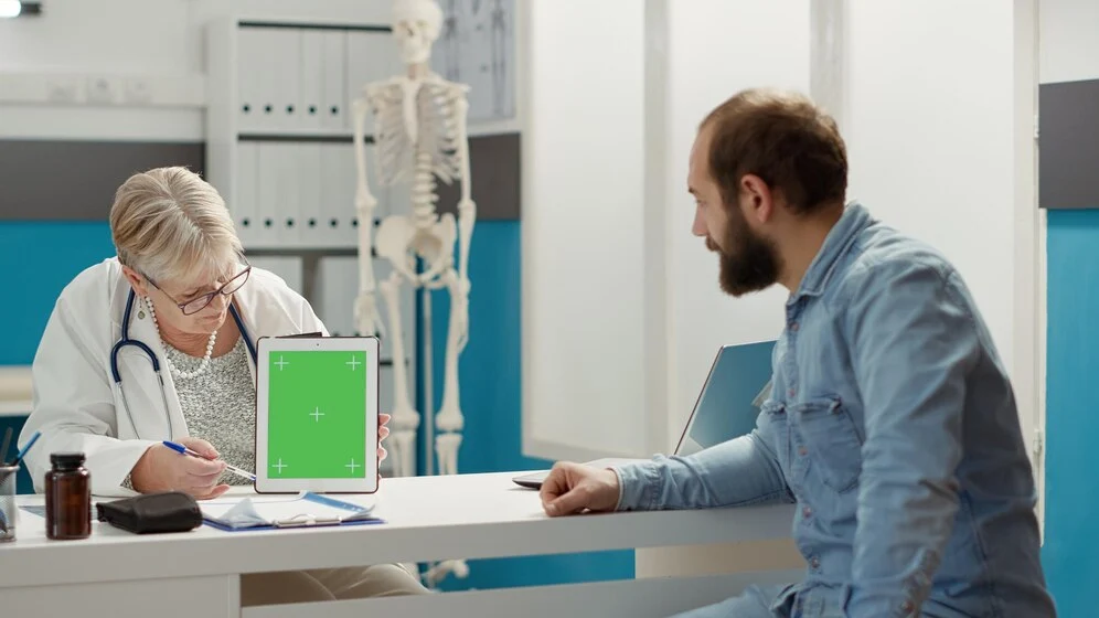 A person sitting at a desk with a computer, filling out medical billing forms.