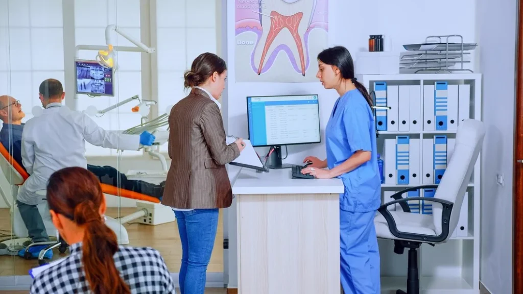 Two people working on computers in a dental office, focusing on orthopedic medical billing.
